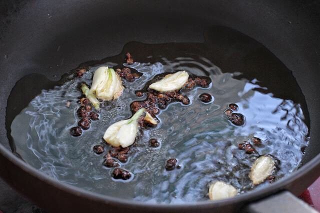 蒜苔炒腊肠,锅中倒适量食用烧热，先放入花椒粒炒出香味，接着放入大蒜炒香。
