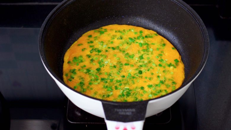 日式火腿鸡蛋卷,把蛋黄和韭菜碎也倒入锅中摊平摊匀煎熟盛出。