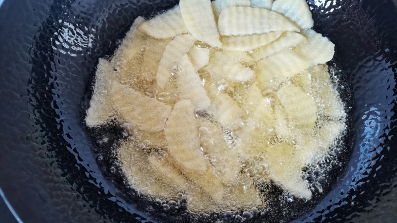 洋葱炒土豆片,锅里倒入稍多点的油，油热放入土豆片炸软