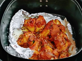 蜜汁烤鸡腿,20分钟后，鸡腿经过高温烘烤，出来很有油脂，连油纸一起拿出来。