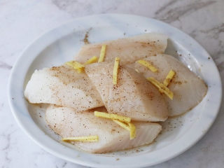 香煎龙利鱼,接着将解冻好的比目鱼洗净加入姜丝、黑胡椒粉、盐，抓匀腌制15分钟