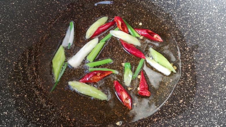 芹菜炒豆干,炒锅内倒适量的食用油烧热，下入小葱和干红辣椒炒香。