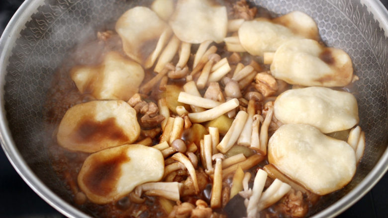 地锅鸡,加入海鲜菇，把松弛好的面团分成大小均匀的小面团，搓圆按扁后轻轻扯成薄饼，码放在锅的周围。