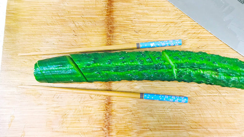 簑衣黄瓜,用筷子夹住，刀倾斜45度，切至三分之二处，不要切断