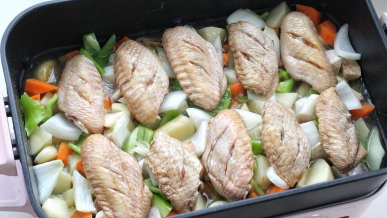土豆炖鸡翅,然后将腌制好的鸡翅依次摆放在蔬菜上面，盖上锅盖小火焖煮十分钟。