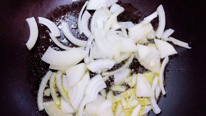 孜然杏鲍菇,锅中倒入油，加热至五成热，放入洋葱翻炒均匀。