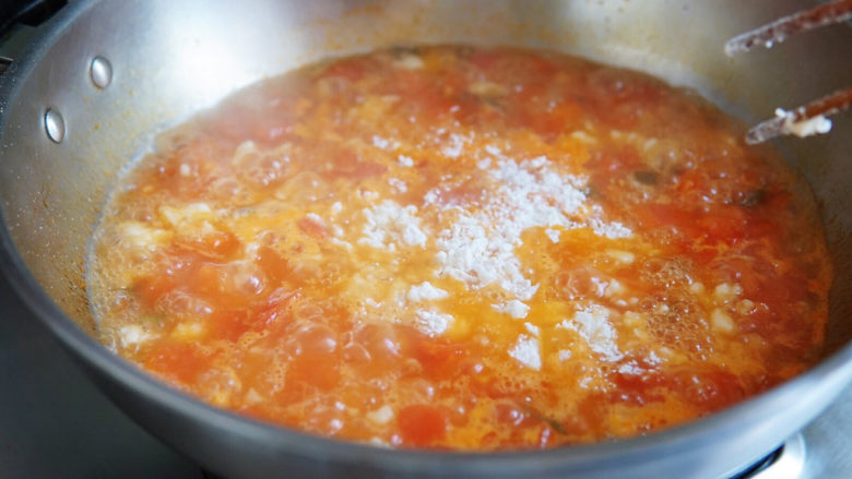 西红柿疙瘩汤,并用筷子搅拌打散面团