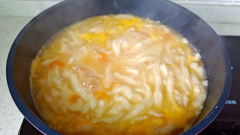 西红柿疙瘩汤,面碗倾斜，筷子沿着面碗把面糊一根一根往往下划。