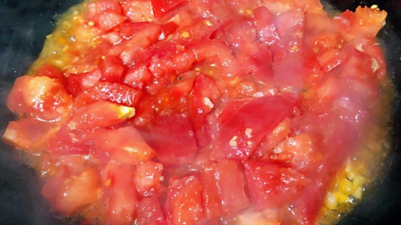 西红柿炒土豆片,锅中倒入底油加热放入蒜粒爆香再放西红柿大火快速翻炒
