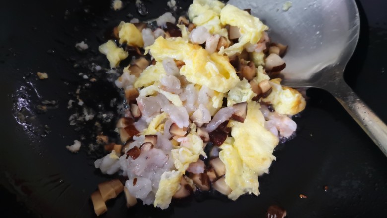 香菇鸡肉炒饭,待鸡蛋液定型用铲子边铲边叉成小块，倒入香菇丁和虾仁丁
