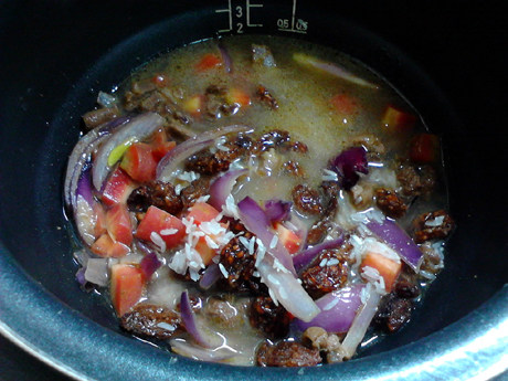 羊肉抓饭,最后把大米均匀铺在葡萄干上，加入清水，水量与大米持平。