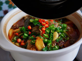 鱼头豆腐煲,撒上红绿辣椒，一把小葱绿，在辣椒上滋一汤勺热油。