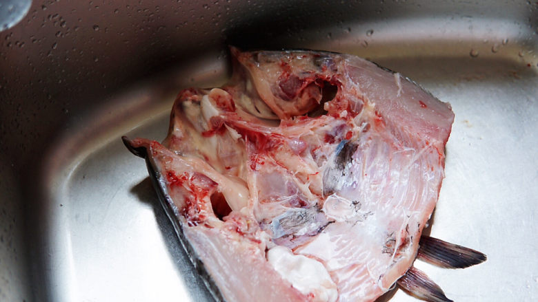 鱼头豆腐煲,鱼头从中间部位切开。冲洗干净内部血渍，控水。