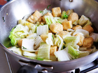 油豆腐炒白菜,油豆腐入锅一同翻炒片刻，加一汤碗的水，中火慢慢煮开，至白菜软烂。