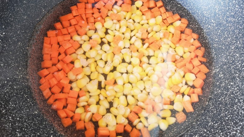 胡萝卜炒玉米,锅里放水烧开，下入胡萝卜丁和玉米粒焯水，捞出控一下水分备用。