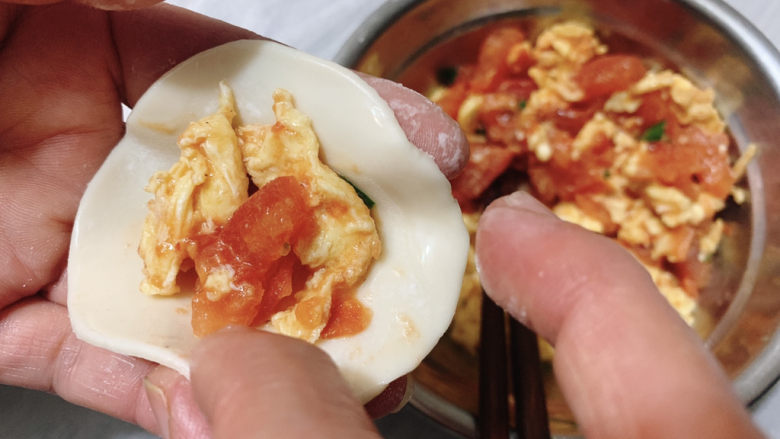 西红柿鸡蛋饺子,食指蘸适量水，在饺子皮外圈，然后捏紧饺子。