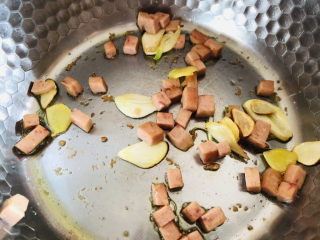 上汤菠菜,姜片跟蒜瓣炒香以后放入切好的午餐肉继续翻炒均匀。