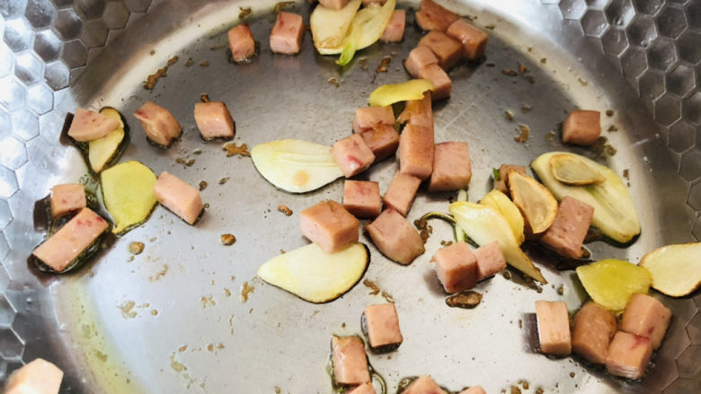 上汤菠菜,姜片跟蒜瓣炒香以后放入切好的午餐肉继续翻炒均匀。