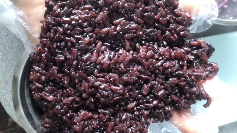 紫米芋泥八宝饭,戴上手套，取一大块糯米饭在手掌上摊平。