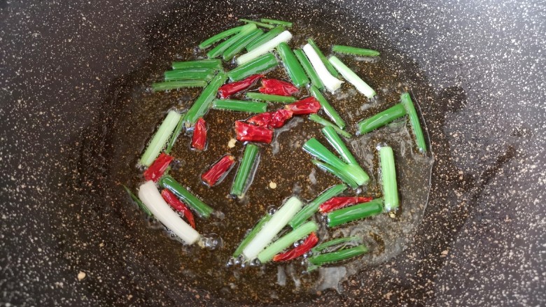 油焖春笋,炒锅内倒适量的食用油烧热，下入葱段和干红辣椒炒香。