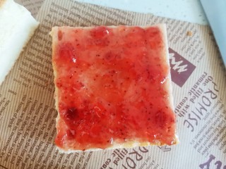 草莓果酱蛋糕,再盖上另一片，上面也抹上草莓酱，从中间切成两半成长方形