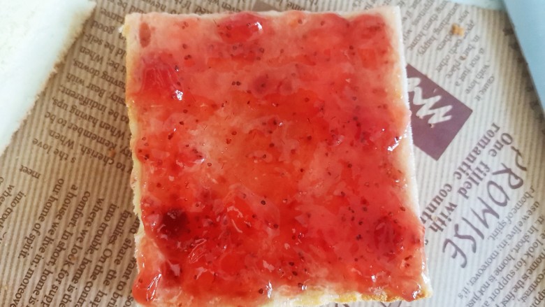 草莓果酱蛋糕,再盖上另一片，上面也抹上草莓酱，从中间切成两半成长方形
