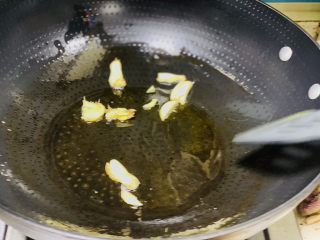 腊肉炒花菜,锅里中火烧烤，倒入食用油，加入蒜头和姜片爆香油锅；