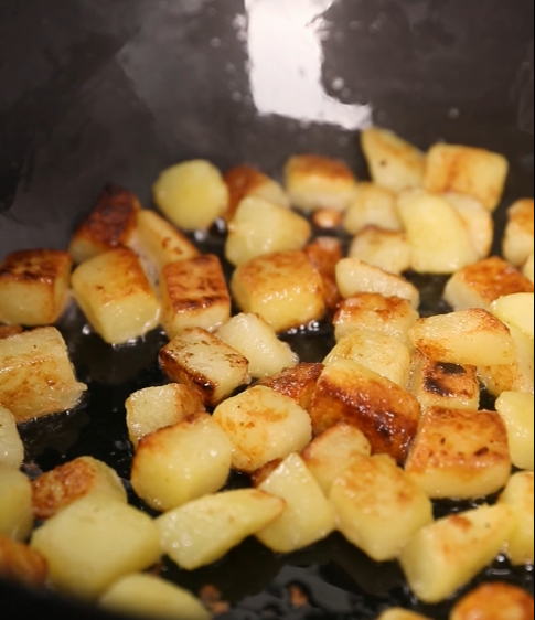 孜然火腿土豆丁,锅中倒入食用油，倒入煮好的土豆丁，煎至两面金黄色