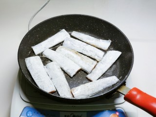 干煎带鱼,放入包裹了面粉的鱼段。