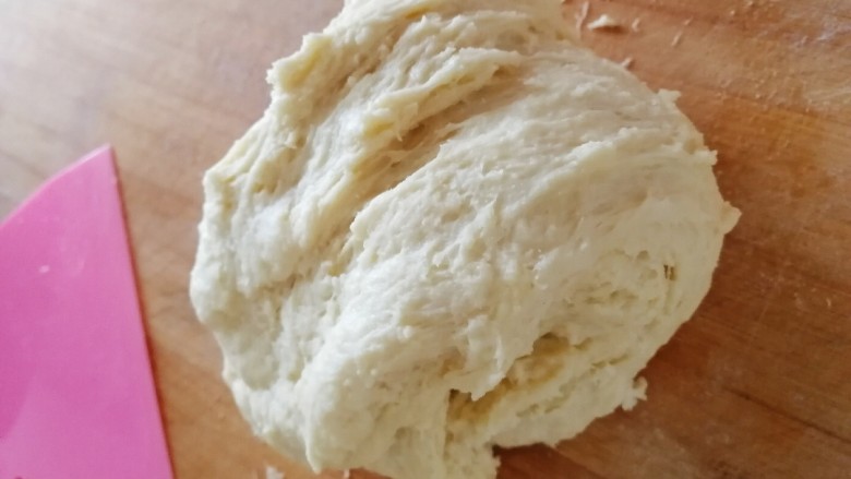 酸奶面包,用刮板收起粘在面板上的面团，折叠后再摔打。