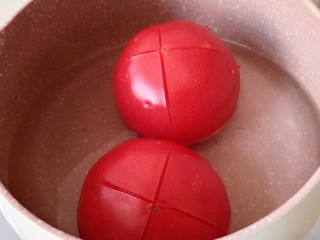 番茄牛肉面,炖肉的时候处理一下番茄。把番茄底部划十字刀，放进奶锅里，倒入热水，烫一两分钟。热水最好没过番茄。如果水少，可以来回转锅，让番茄每个面都被烫到