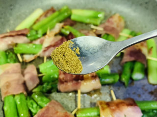 培根芦笋卷,转中小火，慢煎，一面焦黄，撒少许孜然粉和少许黑胡椒粉