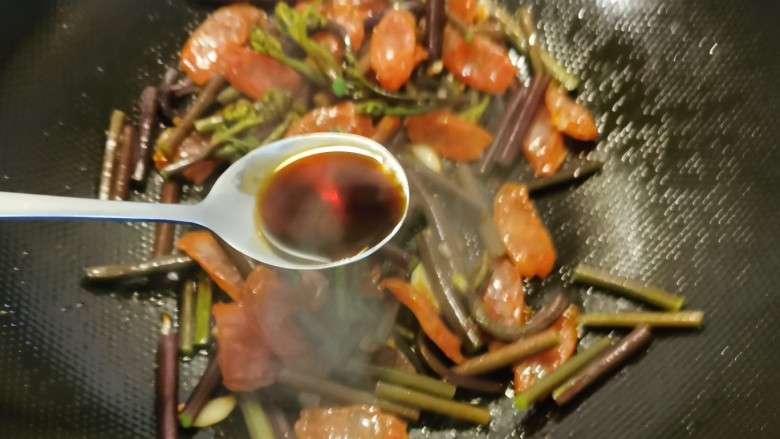 蕨菜炒腊肉,倒入鲜贝露增鲜。