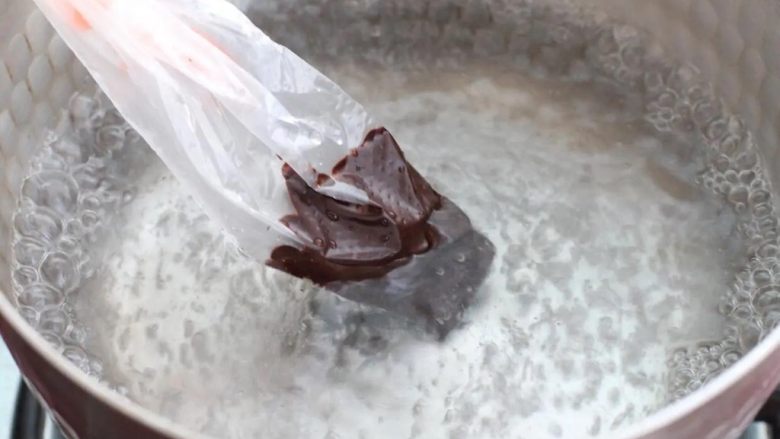 棉花糖饼干,将适量黑巧克力放进裱花袋里，隔水加热至融化状态。