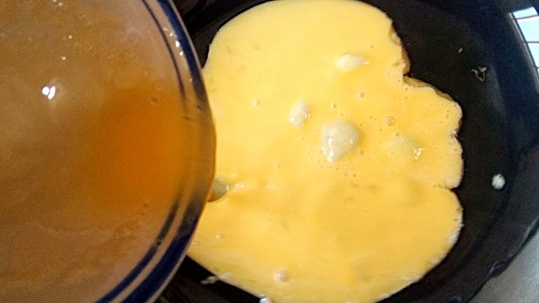 香椿炒蛋,锅中适量油烧至七成热时，倒入打好的鸡蛋液。