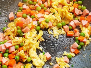 菠萝蛋炒饭,加入胡萝卜，青豆，火腿肠翻炒均匀。