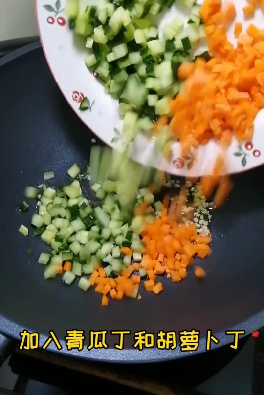 时蔬炒黑米饭,香加入青瓜丁和胡萝卜丁，翻炒片刻