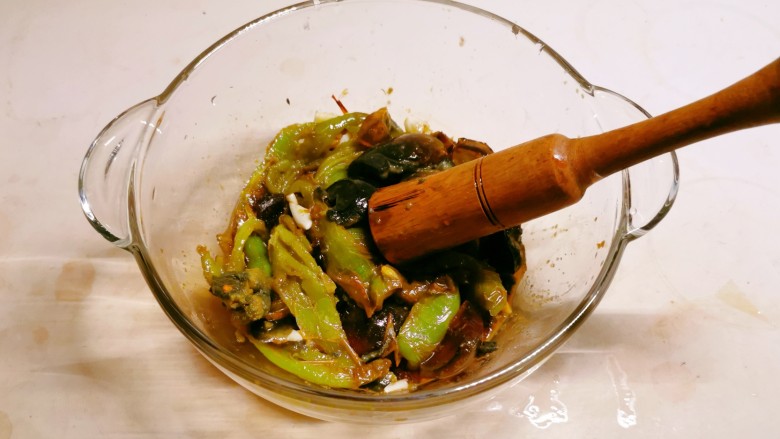 擂椒皮蛋,用擂槌将青椒与皮蛋捣散入味。