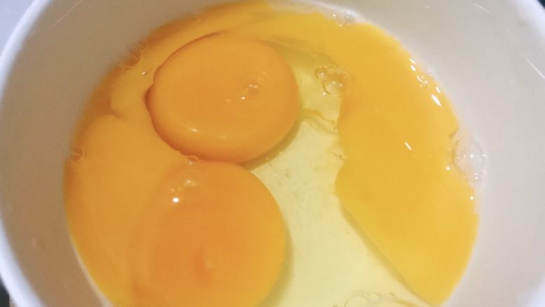 香菇炒鸡蛋,两个鸡蛋磕入碗中