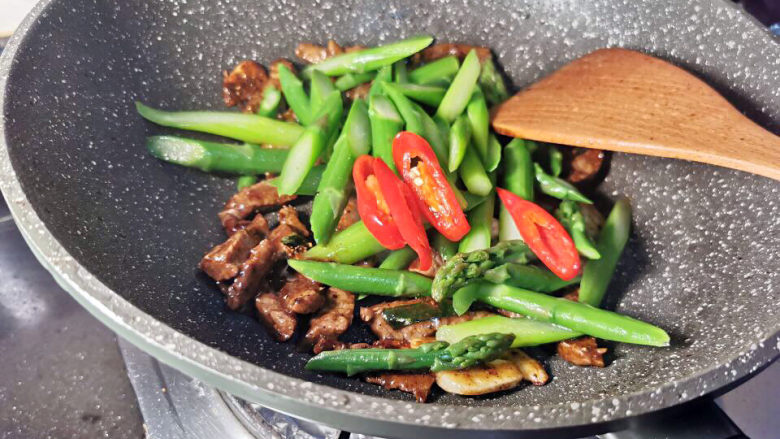 芦笋炒牛肉,牛肉锅中加入芦笋及红椒拌匀即可装盘