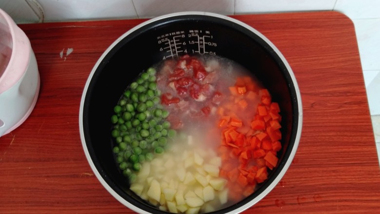 懒人焖饭,把准备好的豌豆，胡萝卜丁，土豆丁，肉丁摆放在大米上面