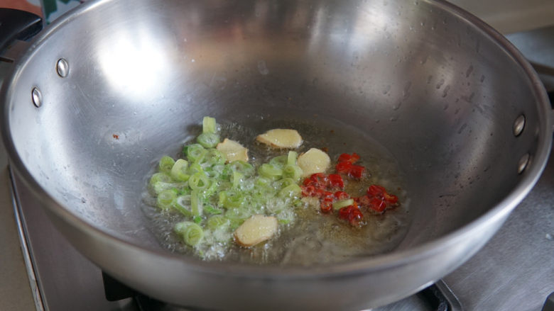 雪菜炒蚕豆,再下入辣椒圈、小葱煸香