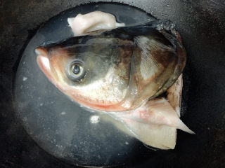 双椒鱼头,红鲢鱼头三去洗净后，入锅中用热水冲烫，去腥去血水后捞出沥干水分。