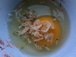 芦笋炒鸡蛋,鸡蛋打入碗中，加入虾米。