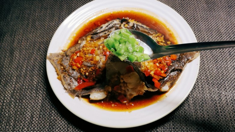 双椒鱼头,鱼蒸好后取出，将炒好的青椒丁均匀分布到鱼身上。