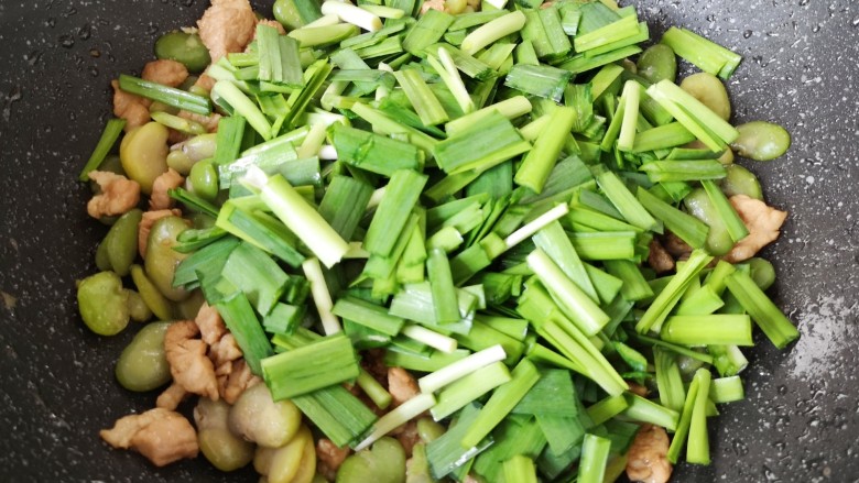韭菜炒蚕豆,下入韭菜翻炒均匀。