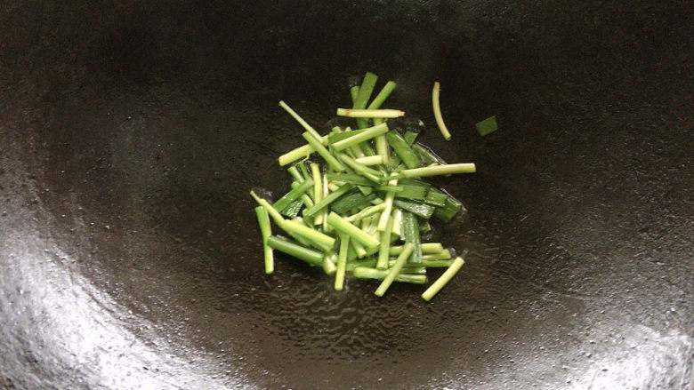 韭菜炒蚕豆,锅烧热油，用韭菜根先行煸炒出香味。