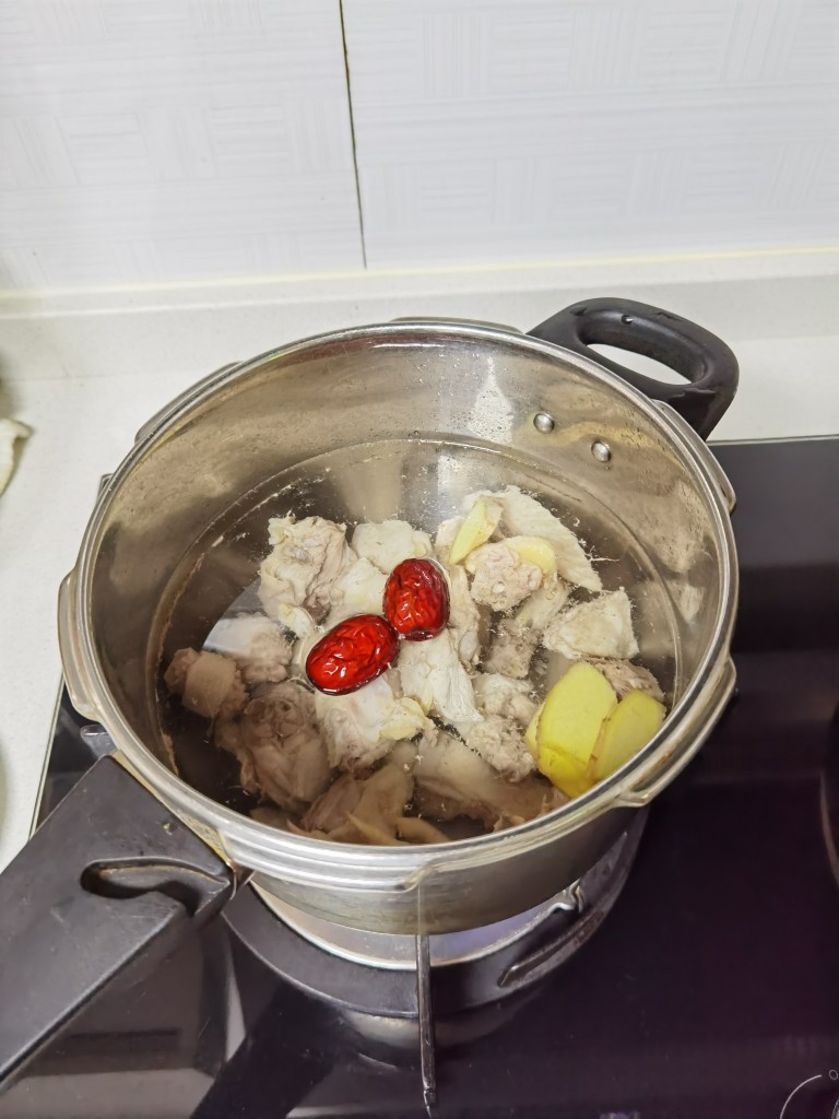 舌尖上的美味～松茸养生鸡汤,把鸡肉倒入锅中焯一遍水后，换一锅清水煮开后撇去浮末后加入红枣和姜片。