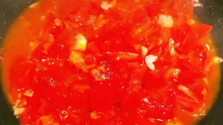 西红柿炖牛肉,锅中倒入底油加热放入蒜粒爆香再放入西红柿大火快速翻炒出汤汁
