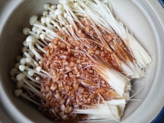 金针菇豆腐煲,将洗净的金针菇铺在砂锅底部，将煮开的蒜末料汁浇在金针菇上。